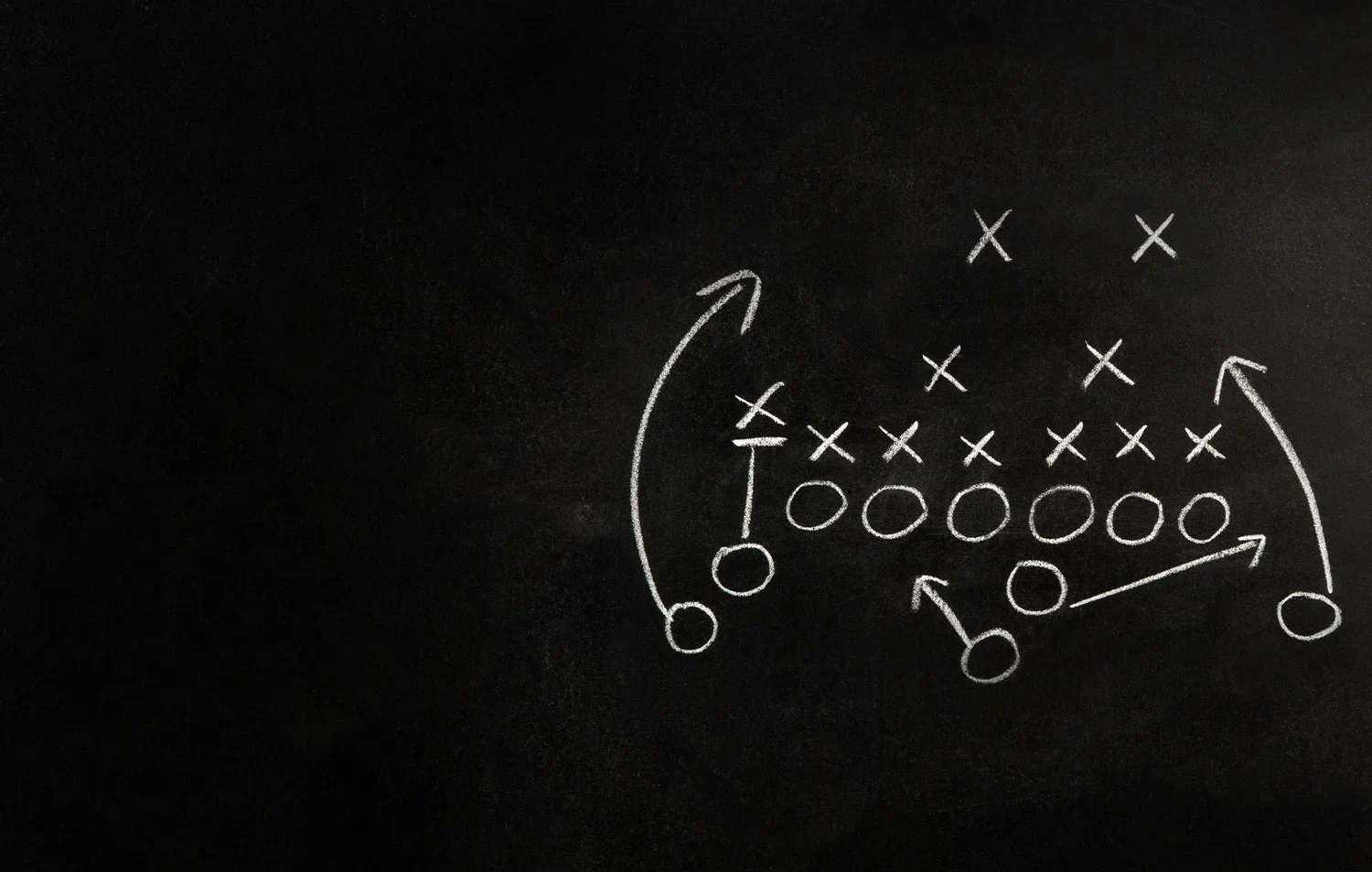 A chalkboard displaying a detailed football play diagram with lines and player positions